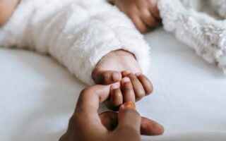 Mom holding baby's hand trying to bond.