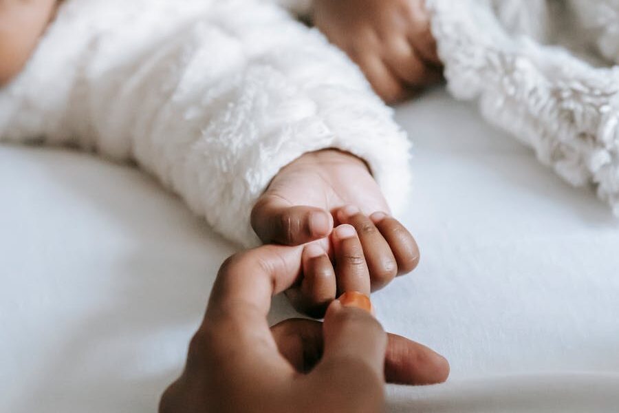 Mom holding baby's hand trying to bond.