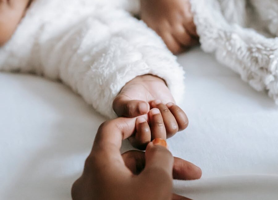 Mom holding baby's hand trying to bond.