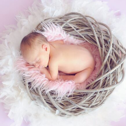 Baby curled up in a basket.