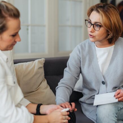 Woman holding other woman's hand and giving her unsolicited advice.