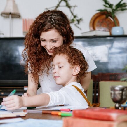 Mom sitting at the table spending time with her son as he draws.