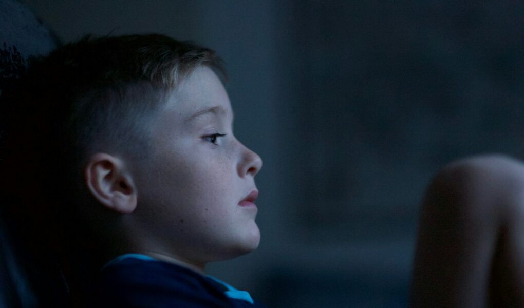 Child sitting in the dark looking sad.