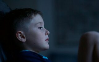 Child sitting in the dark looking sad.