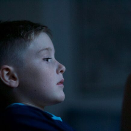 Child sitting in the dark looking sad.