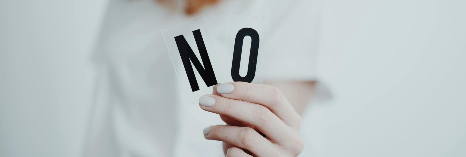 Woman holding the letters N and O to make the word no.