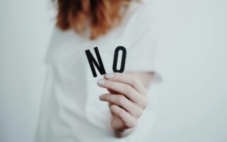 Woman holding the letters N and O to make the word no.