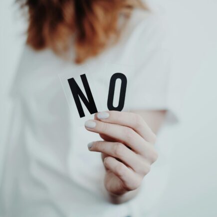 Woman holding the letters N and O to make the word no.