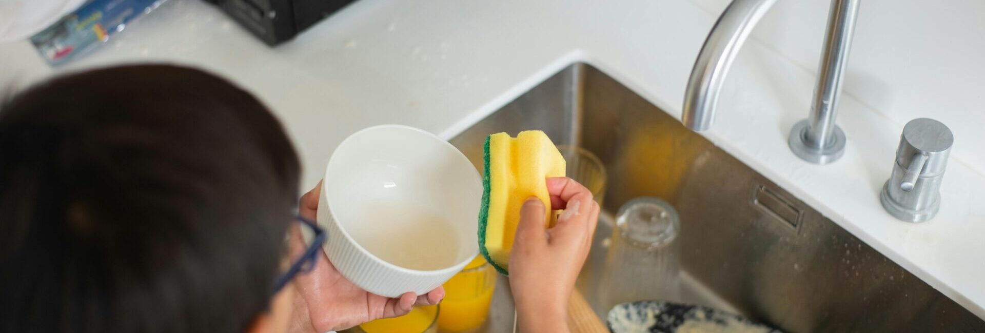 Boy cleaning dishes as part of his household chores.