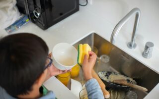 Boy cleaning dishes as part of his household chores.