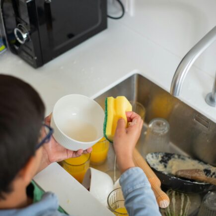 Boy cleaning dishes as part of his household chores.