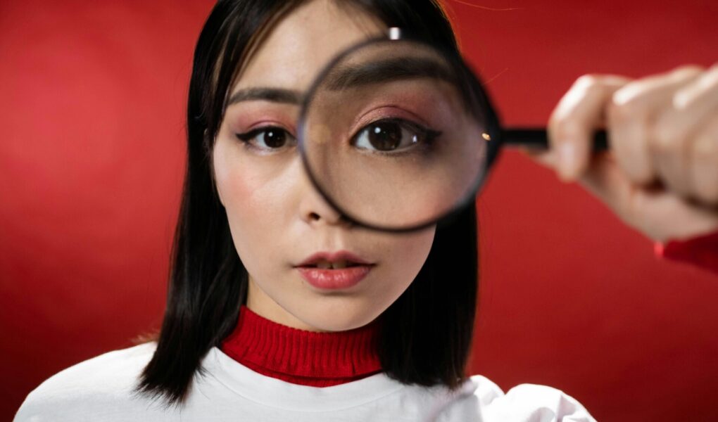 Woman looking through a magnifying glass.