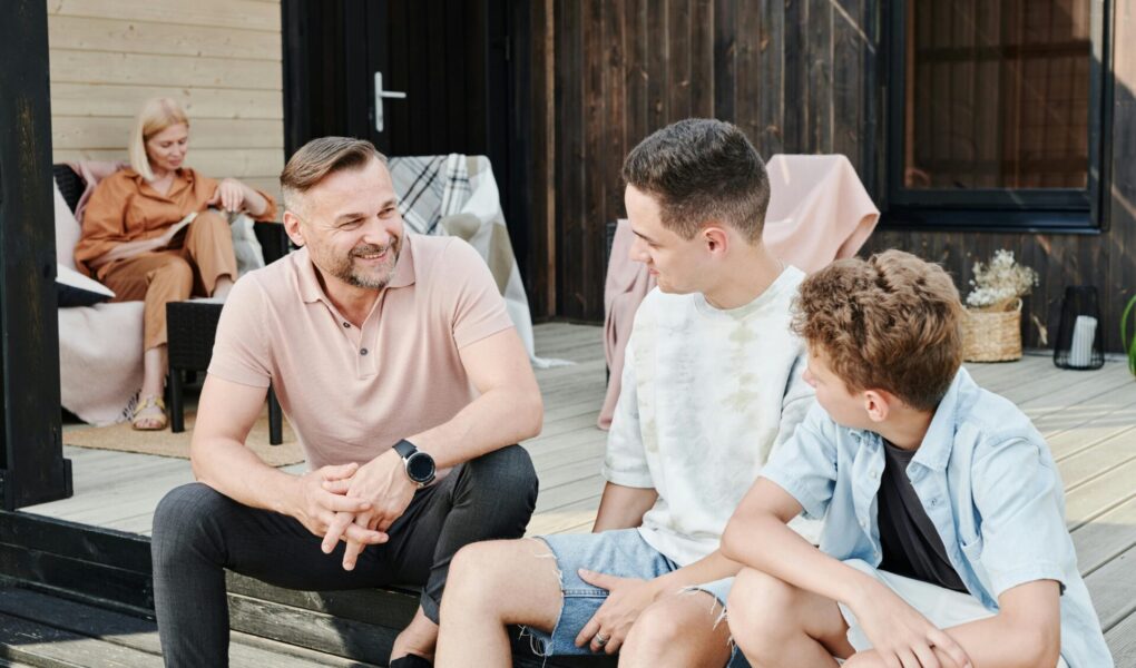 Parents spending time with their 2 sons. Dad is sitting with his sons having a conversation.