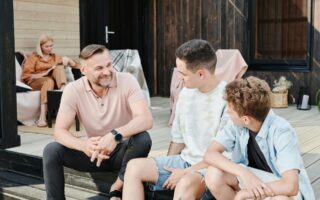 Parents spending time with their 2 sons. Dad is sitting with his sons having a conversation.