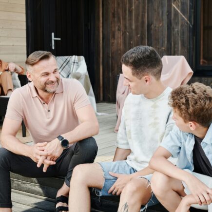 Parents spending time with their 2 sons. Dad is sitting with his sons having a conversation.