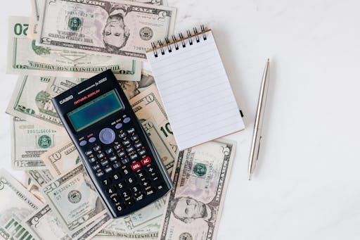 Money on the table alongside a calculator, notepad, and pen.