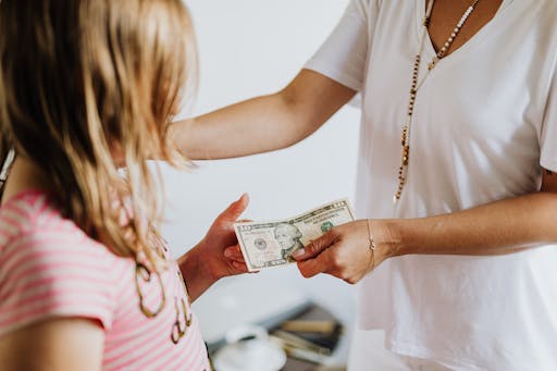 Mom handing allowance to her child.