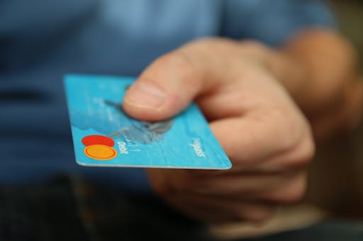 A hand holding out a credit card.