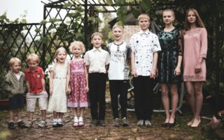 9 siblings standing in a row from youngest to oldest.