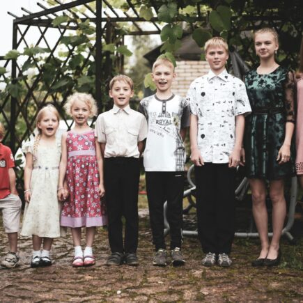 9 siblings standing in a row from youngest to oldest.
