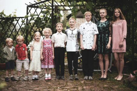 9 siblings standing in a row from youngest to oldest.