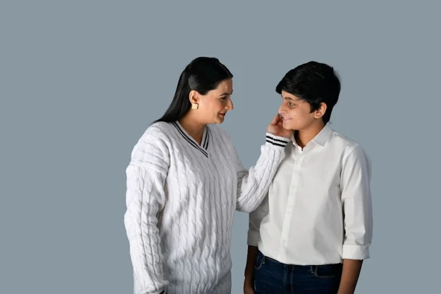 Mom is warmly looking at her son with her hand on his face. Talking to children about peer pressure is an act of love from a parent.