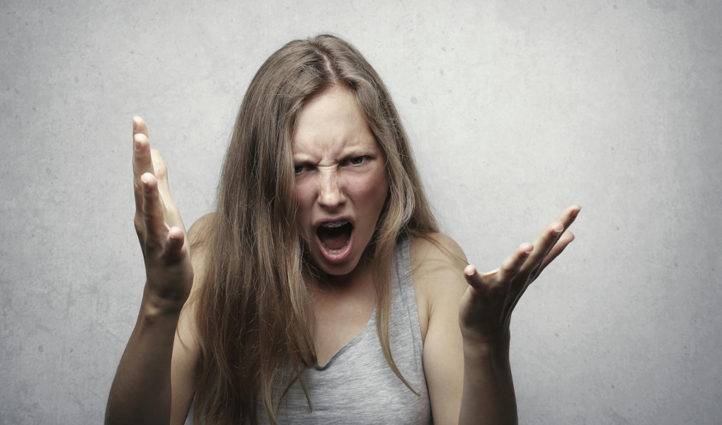 Angry woman with arms extended representing a parent yelling at their kids.