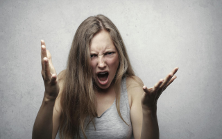 Angry woman with arms extended representing a parent yelling at their kids.