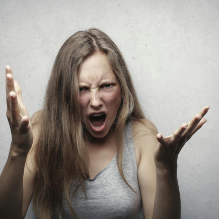 Angry woman with arms extended representing a parent yelling at their kids.