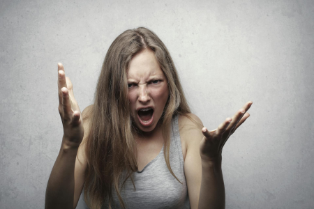 Angry woman with arms extended representing a parent yelling at their kids.